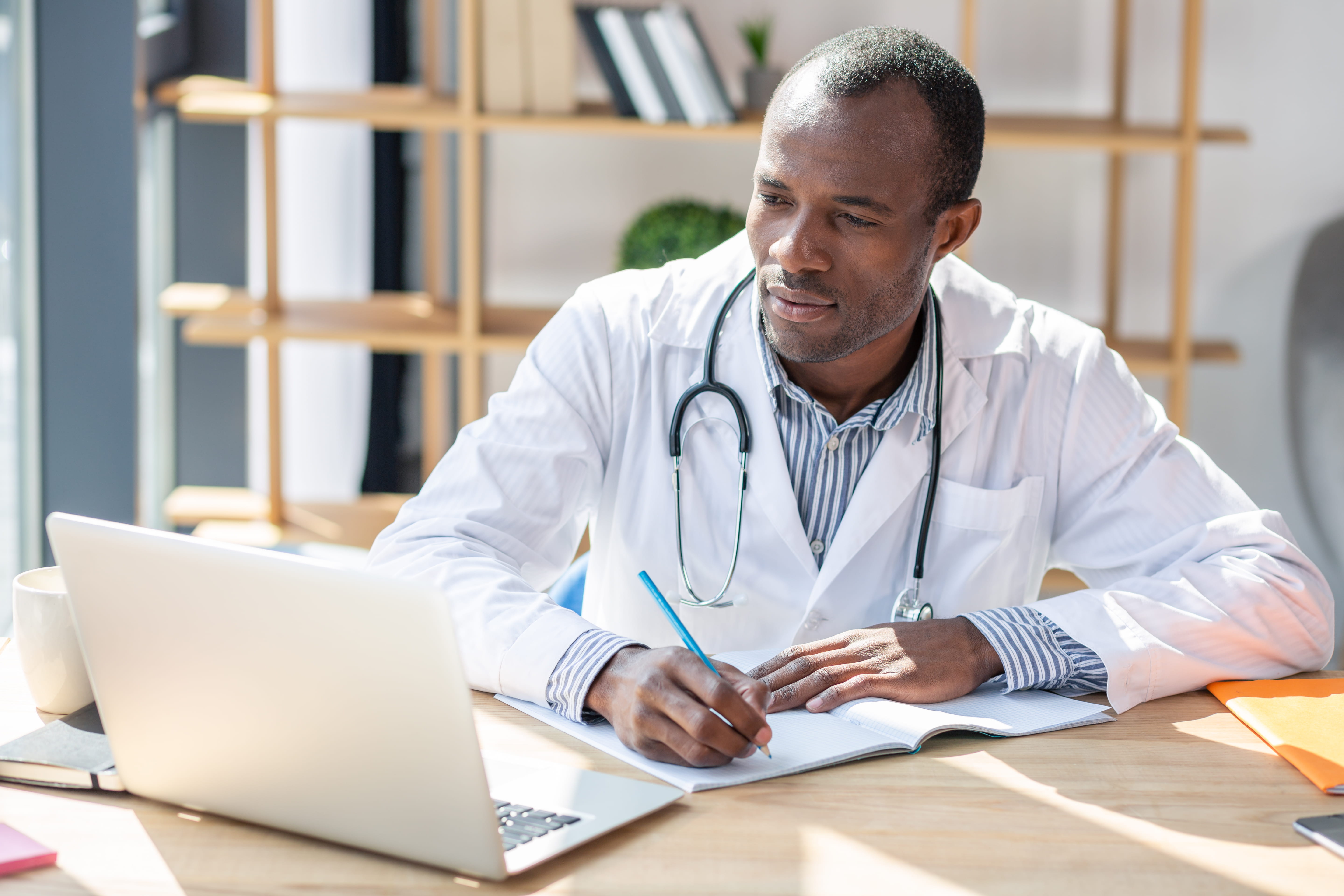 Doctor looks at laptop and takes notes